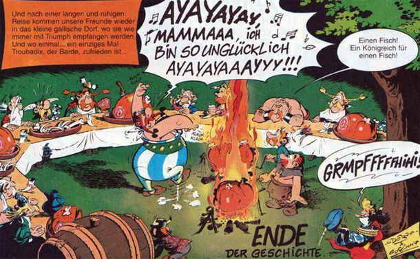 Die Gallier beim abendlichen Festbankett. Obelix tanzt in der Mitte am Feuer und singt auf spanische Weise. Die Gäste sind schockiert. Troubadix liegt gefesselt und geknebelt unter dem Baum und freut sich sichtbar.