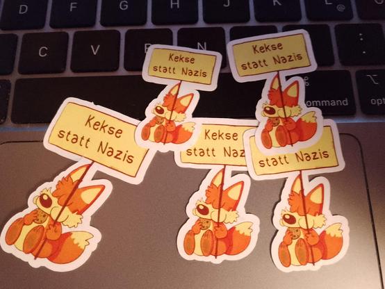 Ein paar Sticker mit einem Fuchs der einen Keks futtert und ein Schild hält mit "Kekse statt Nazis" drauf.